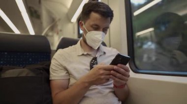 Yüz maskesi takan bir banliyö sakini Almanya 'da sessiz bir S-Bahn treninde telefonunu kontrol ediyor. Toplu taşımayı, enfeksiyon korkusunu ve solunum hastalıkları sırasında yaşamı temsil ediyor.. 