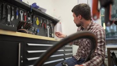 Bisiklet tamircisi, bisiklet atölyesinde tekerlek ve çakıl bisikletinin merkezini tamir ediyor. Bisiklet tamircisinde çalışan bisikletçi çakıl merkezini tamir ediyor. Bisiklet onarımı, servis ve bakım. 