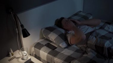 Adam geceleri uykusuzluk çekiyor, yatakta hayal kırıklığına uğramış bir şekilde yatıyor, gözlerini ovuşturuyor, su içiyor, telefonunu kontrol ediyor, sonra da kafasını umutsuzlukla örtüyor.. 
