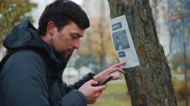 Adamın biri parkta bir ağacın içinde bir köpeğin kaybolmasıyla ilgili bir ilan okuyor ve afişte belirtilen telefon numarasından sahibini arıyor. Kayıp evcil hayvanları arama teması. Kayıp köpek.