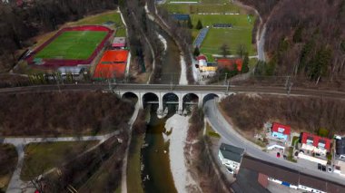 Traunsteiner Viaduct 'un hava görüntüsü, Almanya' nın Bavyera bölgesindeki Rosenheim-Salzburg hattındaki taş demiryolu köprüsü. Beş kemerli Traun Nehri manzaralı bahar manzaraları arasında uzanıyor. Luftaufnahme, Deutschland. 
