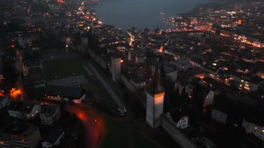 Musegg Wall ve dokuz kulesi geceleri İsviçre 'nin Lucerne kentindeki parlayan şehre bakıyor. Lucerne 'in ortaçağ savunması. Museggmauer Luzern und ihre neun Tuerme Luftaufnahme bei Nacht. 