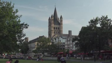 20 Temmuz 2024. Köln, Almanya. Gross Sankt Martin am Fischmarkt in Koeln, Deutschland im Sommer Blick vom Rheinufer. Büyük St. Martin Kilisesi, Köln. İnsanlar rıhtımda yürüyor ve dinleniyor.. 