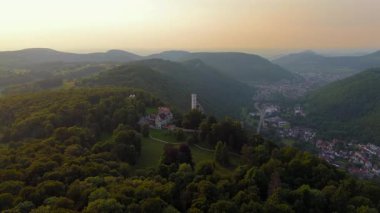 Lichtenstein Kalesi 'nin hava günbatımı görüntüleri. Honau, Almanya' nın yukarısındaki Albtrauf sırtına tünemiş. Bu romantik dağ kalesi, orman ve sarp kayalıklarla çevrili ılık bir ışıkla parıldıyor..