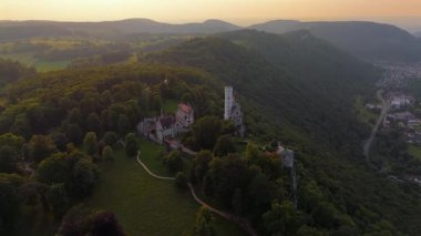 Cinematische Drohnenszene Schloss Lichtenstein auch als Maerchenschloss Wuerttemberg in Baden-Wuerttemberg im Landkreis Reutlingen, Deutschland. Sommerliches Licht, umgeben von Wald und Felsen. 