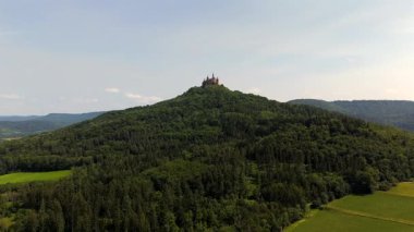 Die Burg Hohenzollern liegt auf dem Hohenzollern bei Bisingen, Baden-Wuerttemberg. Diese Luftaufnahme zeigt die majestatische Gipfelburg im Sommer ueber den Waeldern der Schwaebischen Alb.