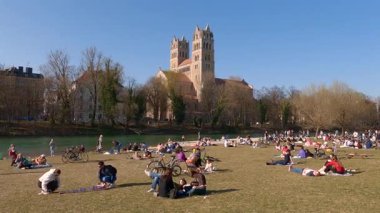 27 Nisan 2022. Münih, Almanya. İzleyiciler St. Maximilian Kilisesi 'nin yakınlarındaki ilk sıcak günlerin tadını çıkarıyorlar. Bisikletçiler, aileler ve arkadaşlarla Münih' in yeşil kalbinde güneşleniyorlar.. 