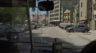 17 Ağustos 2023, Porto, Portekiz. Portekiz 'in Oporto kentindeki şehir otobüsünün ön camından yaz şehri manzarası. Kamu otobüsünün içinde, şehir trafiğine, yoğun yola, park edilmiş arabalara, şehir hayatına bakıyor.. 