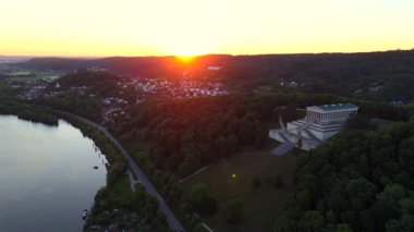 Almanya, Regensburg yakınlarındaki Braeuberg tepesindeki Walhalla anıtının günbatımı hava manzarası. Bu neoklasik tapınak Tuna Nehri 'ne bakıyor. Bavyera manzarası üzerinde altın saat ışığı parlıyor.. 