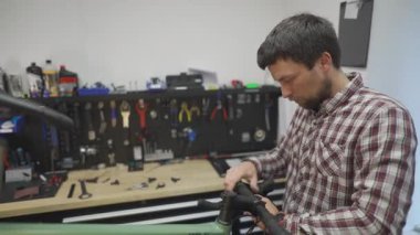 Bisiklet tamircisi bisiklet tamir atölyesindeki çalışma yerinde bisiklet gidonu etrafına bisiklet bandı sarar. Bisiklet mühendisi gidon bandı atölyedeki iş yerinde çakıl bisikleti üzerinde. 