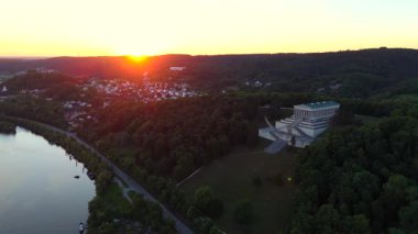 Donaustauf, Bavyera 'da gün batımında Walhalla. Drone görüntüleri, Almanya 'nın Regensburg yakınlarındaki tepelerin üzerinden panoramik manzaralı ve yumuşak akşam ışığında Tuna Nehri üzerindeki mermer tapınağı yakalıyor.