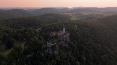 Schloss Lichtenstein Wuerttemberg 'in Drone görüntüleri, Reutlingen yakınlarındaki Alman peri masalı kalesi. Manzaralı vadi ve yemyeşil ormanlarla Swabian Jura 'sında çarpıcı bir gün batımı. Maerchenschloss Wuerttembergs