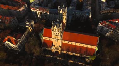 Kath. Pfarramt St. Maximilian Katholische Kirche Münih, Bayern, Deutschland Luftaufnahme 'de. Münih 'teki St. Maximilian' ın sonbahar renkleriyle çevrili, gün doğumunda ayırt edici kuleleri olan hava manzarası.. 