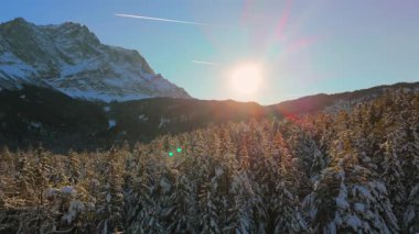 Alman Bavyera Alpleri 'ndeki kar kaplı ağaç tepelerinde nefes kesen hava manzarası, Zugspitze kitsif sergileniyor. Zugspitze Gipfel Wetterstein Dağları 'nın en yüksek zirvesi ve Almanya' nın en yüksek dağı.