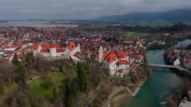Fussen 'in kırmızı çatıları, Gotik mimarisi ve tarihi simgeleri olan eski kasabasının insansız hava aracı görüntüleri. Lech Nehri, Bavyera 'nın zengin kültürel mirasını ön plana çıkararak, pitoresk bir manzara boyunca esiyor..