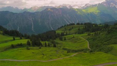 Alman Bavyera Alpleri 'nde Fellhorn ve Kanzelwand' ın çarpıcı alp manzarasının ortasında çakıllı yolda bisikletçi. Yeşil dağlarla, patikalarla ve nefes kesici panoramalarla dolu yaz macerasının havadan görüntüsü..