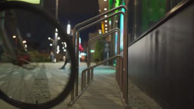 Geceleri süpermarketin yanındaki bisiklet parkında bir adam. Şehirdeki alışveriş merkezinin yanındaki bisiklet standında bir erkek. Bisiklet altyapısı teması. Banliyö görevlisi bisikletini dışarıya park ediyor. Ulaşım ve insanlar kavramı.