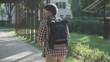 Ekose gömlekli, güneş gözlüklü, güneşli bir parkta, yaz havasında elektrikli scooter süren beyaz bir adam. Konu ekolojisi, çevre koruma, araba egzoz gazlarından kaynaklanan hava kirliliği. Eko taşımacılığı.