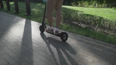 Modern vatandaş kaldırımda eko elektrikli scooterla seyahat ediyor. Ekolojik ulaşım. Elektrikli scooter kullanan genç bir adam. Scooter kiralama servisi. Beyaz erkek, parkta elektrikli taşıma aracında..