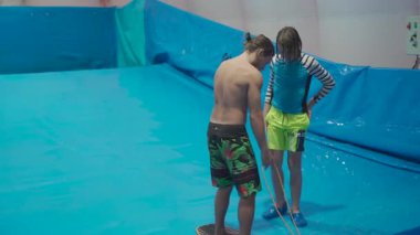 Su sporu aktivitesi, denge konsepti. Küçük sporcu ev içinde sörf yapmaktan hoşlanıyor. Gençler spor kompleksinde simülatörde dalgalarda sörf yapıyor. Sörf koçu ve öğrenci dalga simülatöründe toplandı.