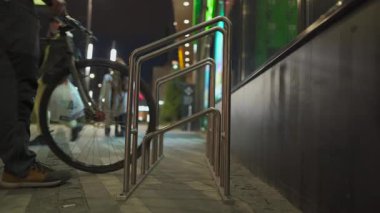 Bisiklet park konsepti. Teslimatçı. Bisikletlerin park yeri. Şehir caddesinde erkek park bisikleti. Akşamleyin süpermarket yakınlarındaki otoparkta bisiklet süren bir bisikletçi. Ulaşım ve insan teması.