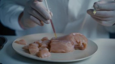 Laboratuvar çalışanı et örneğine ilaç enjekte ediyor. Genetik olarak değiştirilmiş et. Yapay et ürünü, geleceğin gıda teknolojisi. GDO gıda konsepti. Erkek beslenme uzmanı gıda ürünlerini laboratuarda test ediyor..