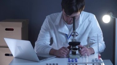 Laboratuvarda mikroskop, bilgisayar ve laboratuvar aletleriyle çalışan bir bilim adamı. Biyolojik teknoloji. Tıp öğrencileriyle ilgili şeyler. Tıbbi asistanım. Bilimsel araştırma. Laboratuvarda dizüstü bilgisayardaki sonuçlar kontrol ediliyor.