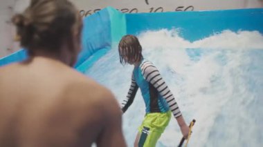 Çocuklar için kapalı sörf kulübü. Tema aktif eğlence ve su üzerinde ekstrem spor. Öğrenci ve koç dalga simülatöründe sörf eğitimi alıyor. Su parkında sörf tahtası..