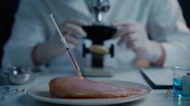 Yemek kalite kontrol konsepti. Laboratuvar asistanı GDO tavuğunu test ediyor. Laboratuvarda örnek et, anabolik ve antibiyotik içeren şırıngalar ve mikroskop inceleyen bilim adamları. Gıda mühendisliği süreci.