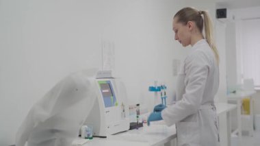 Kadın laboratuvar teknisyeni hematoloji kan analizcisi kullanıyor. Laboratuvarda tıbbi malzemeler. Biyokimyasal ve kan analizi. Tıbbi laboratuvarda otomatik kan testi analizcisi