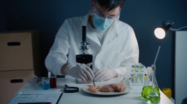 Genç erkek beslenme uzmanı gıda ürünlerini laboratuvarda test ediyor. Genetik mühendisliği, genetik modifikasyon, GDO ve gen manipülasyonu kavramı. Laboratuvarda kültür eti yapan bir bilim adamı. Genetik enjeksiyon.