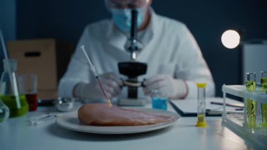 Genç erkek beslenme uzmanı gıda ürünlerini laboratuvarda test ediyor. Genetik mühendisliği, genetik modifikasyon, GDO ve gen manipülasyonu kavramı. Laboratuvarda kültür eti yapan bir bilim adamı. Genetik enjeksiyon.