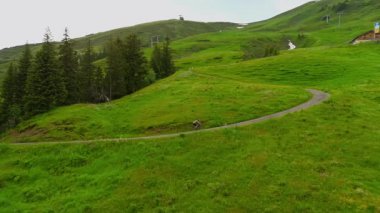 Yazın Alpler 'de kayak merkezinde bisiklet süren hava manzaralı bisikletçi. Bisikletçi Almanya 'nın Bavyera dağlarındaki dağ tatil beldesinde çakıllı bisikletle seyahat ediyor. Alp yamaçlarında bisiklet gezileri 