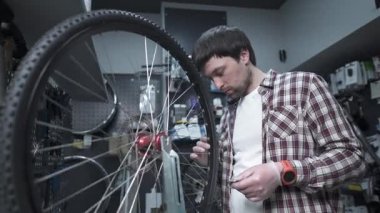Bisikletçi dükkanında tekerlek tamir eden bir bisikletçi. Bir bisiklet tamircisi bisiklet tamirhanesinde konuşan gerilimi düzeltir ve ayarlar. Küçük işletme teması