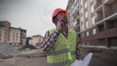 Çalışma süreci. Plana göre çalışan üniforma kontrolünde müteahhit. İnşaatçı telefon görüşmesi ve yeni yerleşim alanının şantiyesinde yürümek. Öncü denetim inşaatı.