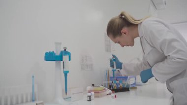Kan testi sırasında şeker kutusuyla laboratuvar teknisyeni geldi. Laboratuvarda tıbbi malzemeler var. Pipeti olan bir bilim adamı hematolojik test yapıyor. Modern laboratuarda pipette dozeri kullanan bir araştırmacı