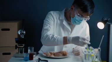 Çiğ tavuk etine genetik enjeksiyon. Bilim adamı et parçalarına enjeksiyon yapıyor. Laboratuvar asistanı GDO tavuğunu test ediyor. Gıda kalite kontrol işçisi. Yiyeceklerde genetik olarak modifiye edilmiş antibiyotik kalıntısı.