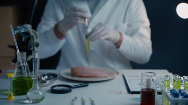 Erkek beslenme uzmanı gıda ürünlerini laboratuvarda test ediyor. Laboratuvar asistanı GDO tavuğunu test ediyor. Tavuk etini test etmek için kimyasalı enjekte ediyorum. Genetik olarak değiştirilmiş gıda, şırınga.