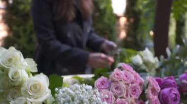 Profesyonel çiçekçi iş başında. Genç ve güzel bir kadın modern yeşil buketi farklı renklerde yapıyor. Çiçekli düğün kemeri tasarımı. İş konsepti. Sonbaharda dışarıda çalışan bir dekoratör..