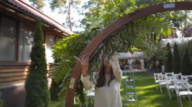 Profesyonel çiçekçi iş başında. Genç ve güzel bir kadın modern yeşil buketi farklı renklerde yapıyor. Çiçekli düğün kemeri tasarımı. İş konsepti. Sonbaharda dışarıda çalışan bir dekoratör..