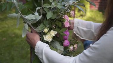 Personel etkinliği ajansı iş başında. Çiçekçiler biner, çiçekleri düğün töreni için kemerle süslerler. Profesyonelce düğün dekorasyonu yaratmak. Çiçekçilik. Düğün kemeri için çiçek kompozisyonuyla çalışan bir dekoratör