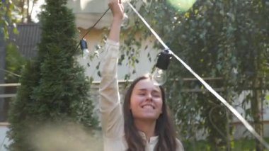 Kadın dekoratör bahçede yapılacak düğün törenleri için siyah tel çelenkler hazırlıyor. Kadın tasarımcı açık hava ışığını düğün töreni için hazırlıyor. Düğün kemerinde çiçekler ve lambalar ile dekorasyon. 