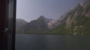 Bavyera 'daki Royal Lake Koenigssee' de huzurlu bir gemi yolculuğu. Video, dik dağ yamaçlarının temiz bir yaz gökyüzünün altında aynaya benzeyen yüzeyle buluştuğu çarpıcı manzarayı gösteriyor.. 