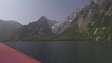 Berchtesgaden Ulusal Parkı 'ndan Konigssee Gölü' nün resimli görüntüsü. Videoda, Bavyera fiyortlarının pürüzsüz yüzeyinde, yoğun ormanlarla çevrili turist elektrikli botu görülüyor.. 