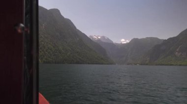 Berchtesgaden Ulusal Parkı 'ndan Konigssee Gölü' nün resimli görüntüsü. Videoda, Bavyera fiyortlarının pürüzsüz yüzeyinde, yoğun ormanlarla çevrili turist elektrikli botu görülüyor.. 