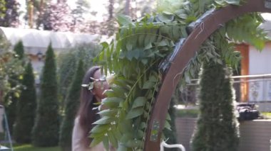 Profesyonel çiçekçi iş başında. Genç ve güzel bir kadın modern yeşil buketi farklı renklerde yapıyor. Çiçekli düğün kemeri tasarımı. İş konsepti. Sonbaharda dışarıda çalışan bir dekoratör..