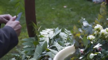 Profesyonel çiçekçi iş başında. Genç ve güzel bir kadın modern yeşil buketi farklı renklerde yapıyor. Çiçekli düğün kemeri tasarımı. İş konsepti. Sonbaharda dışarıda çalışan bir dekoratör..