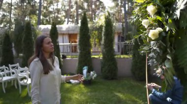 Personel etkinliği ajansı iş başında. Çiçekçiler biner, çiçekleri düğün töreni için kemerle süslerler. Profesyonelce düğün dekorasyonu yaratmak. Çiçekçilik. Düğün kemeri için çiçek kompozisyonuyla çalışan bir dekoratör