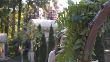 Profesyonel çiçekçi düğün kaydı için festival kemerini dekore ediyor. Kadın düğün dekoru kuruyor. Dekoratör, açık hava düğün törenini çiçekler ve yeşilliklerle süslüyor..