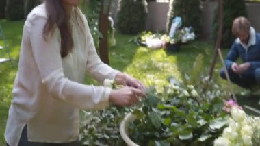 Profesyonel çiçekçi iş başında. Genç ve güzel bir kadın modern yeşil buketi farklı renklerde yapıyor. Çiçekli düğün kemeri tasarımı. İş konsepti. Sonbaharda dışarıda çalışan bir dekoratör..